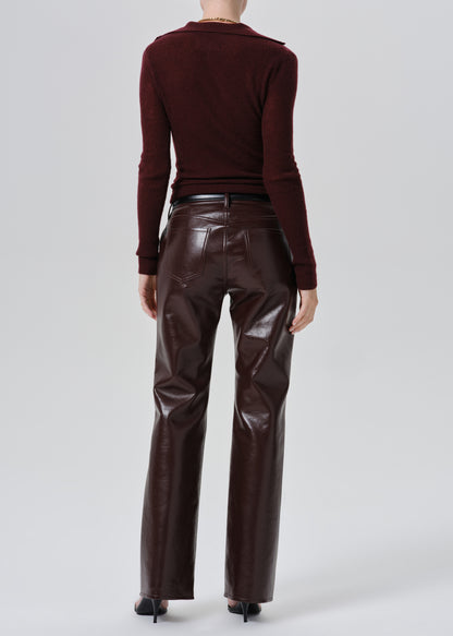 A model shown from the back wearing a dark burgundy long-sleeve top and shiny dark brown faux-leather pants against a grey background.