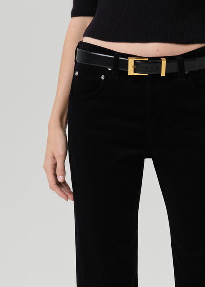 Person wearing black straight leg jeans on a grey background