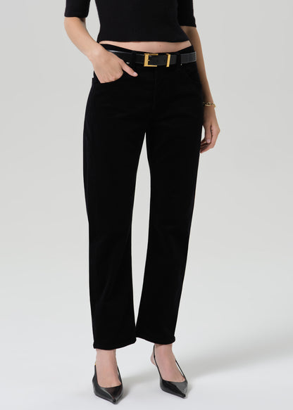 Person wearing black straight leg jeans with a black short sleeve top and black pointed toe heels on a grey background