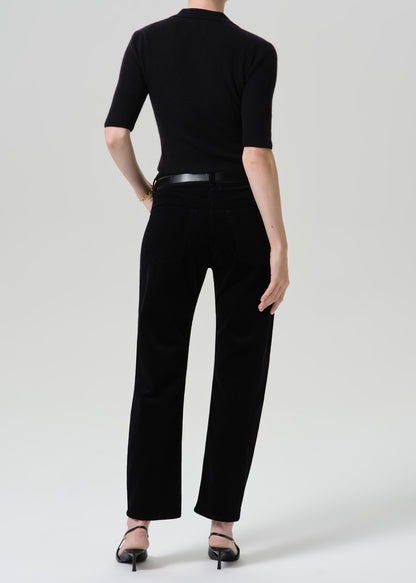 Person wearing black straight leg jeans with a black short sleeve top viewed from the back on a grey background