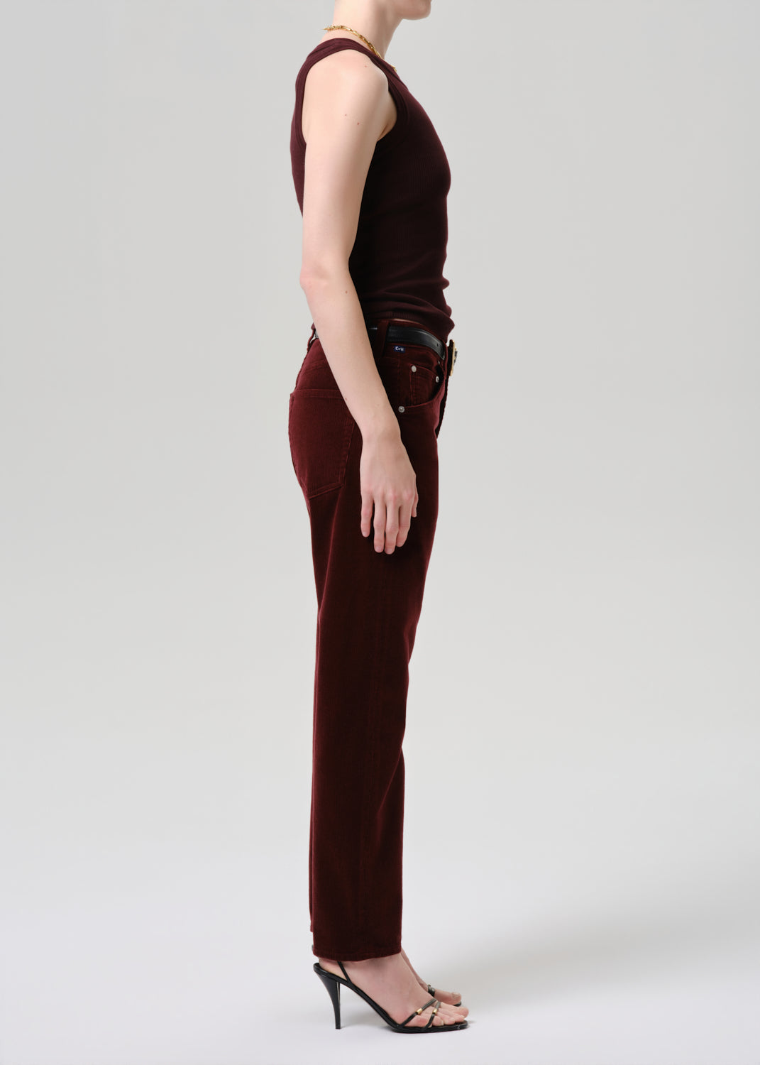 Person wearing a burgundy sleeveless top and pants on a grey background