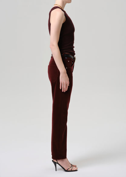 Person wearing a burgundy sleeveless top and pants on a grey background