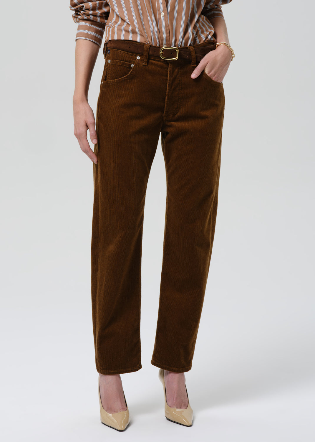 Person wearing brown corduroy pants on a grey background