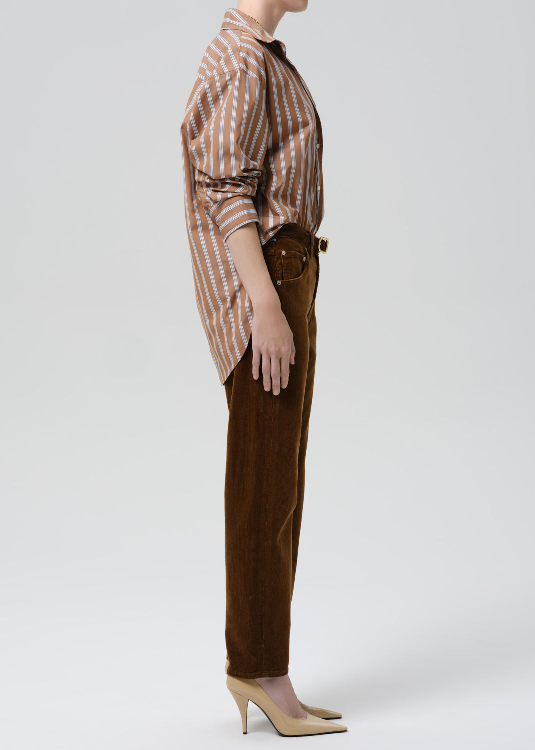 Person wearing a striped shirt and brown pants on a grey background