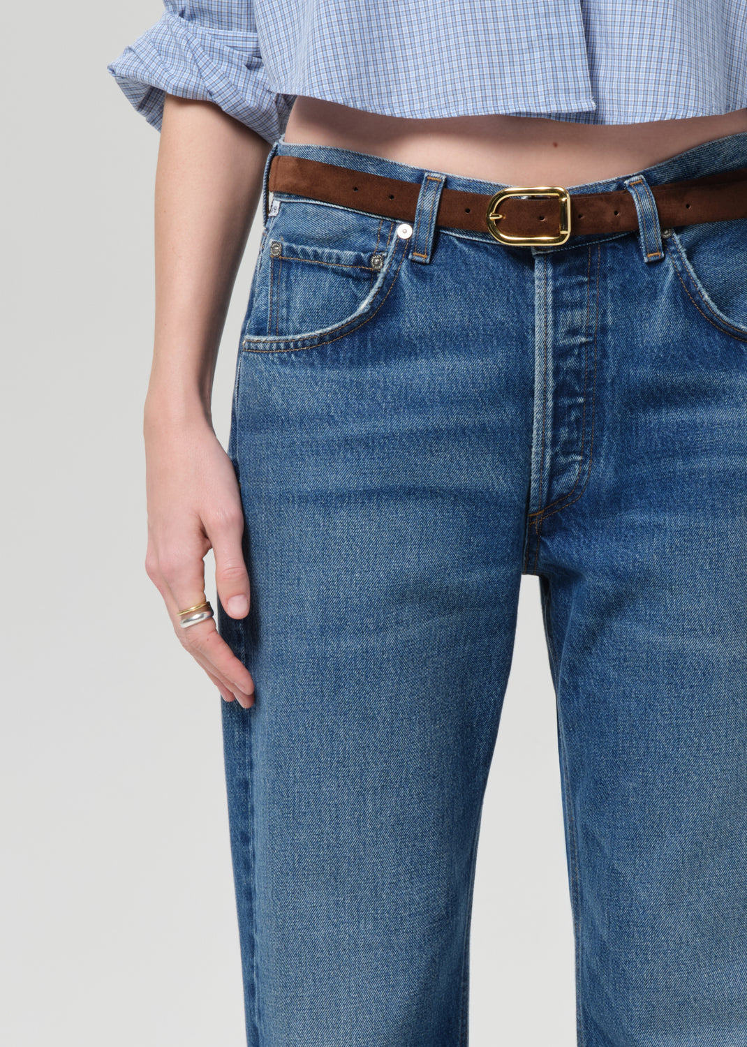 Person wearing a blue shirt and jeans on a plain background