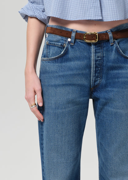 Person wearing a blue shirt and jeans on a plain background