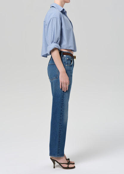 Person wearing a blue shirt and jeans on a plain background