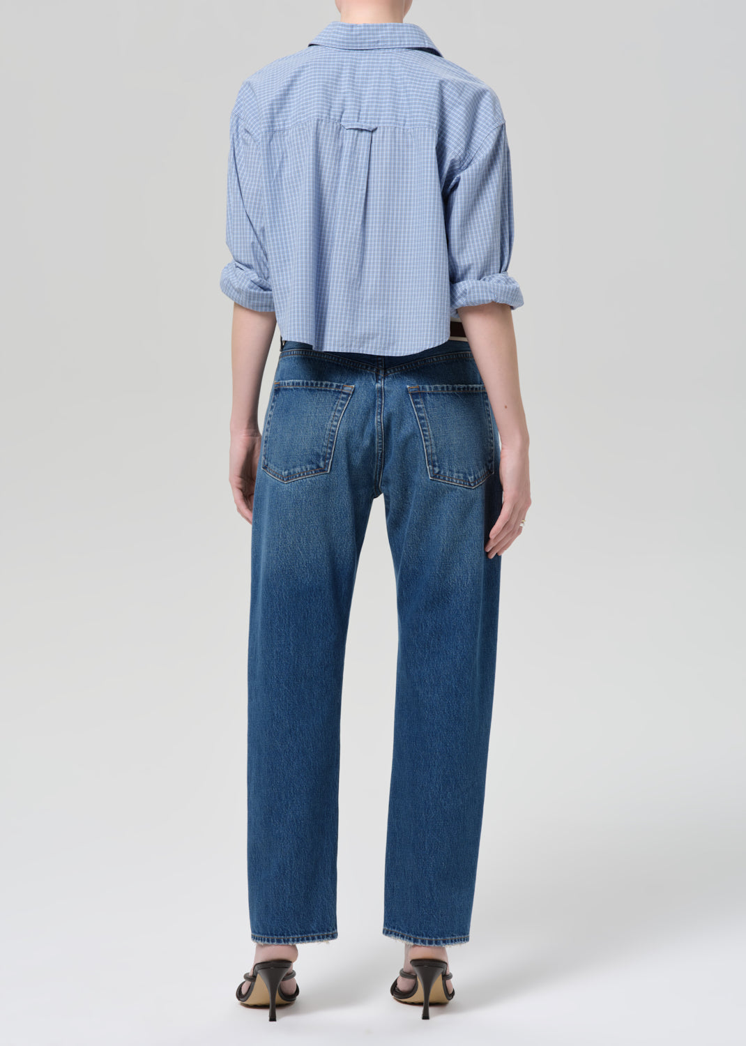 Person wearing a blue shirt and jeans on a plain background