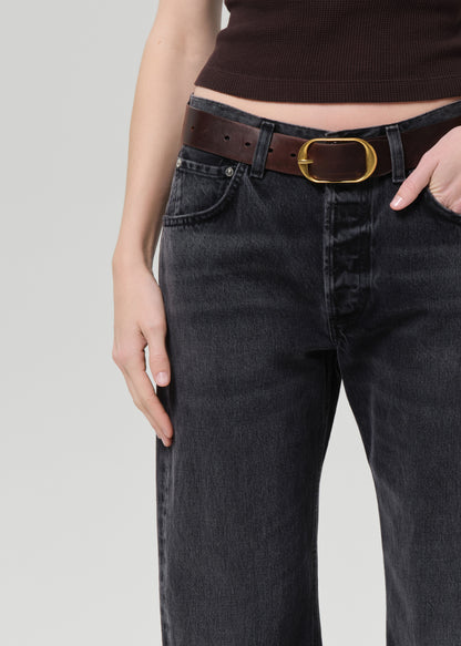 Person wearing black jeans with a brown belt on a light gray background