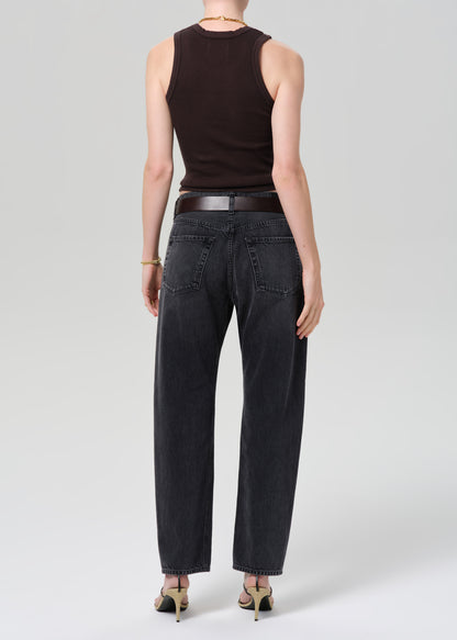 Person wearing a brown sleeveless top and black jeans on a white background
