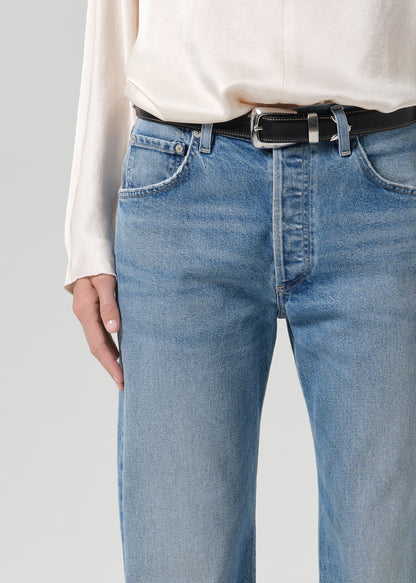 Person wearing blue jeans with cream color satin top