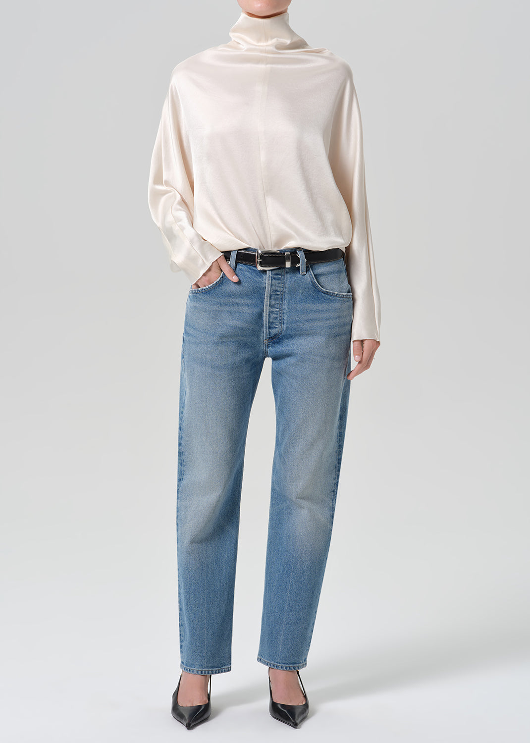 Person wearing blue jeans with cream color satin top