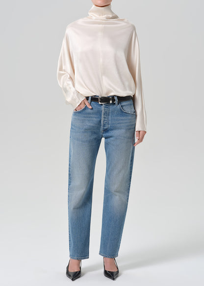 Person wearing blue jeans with cream color satin top