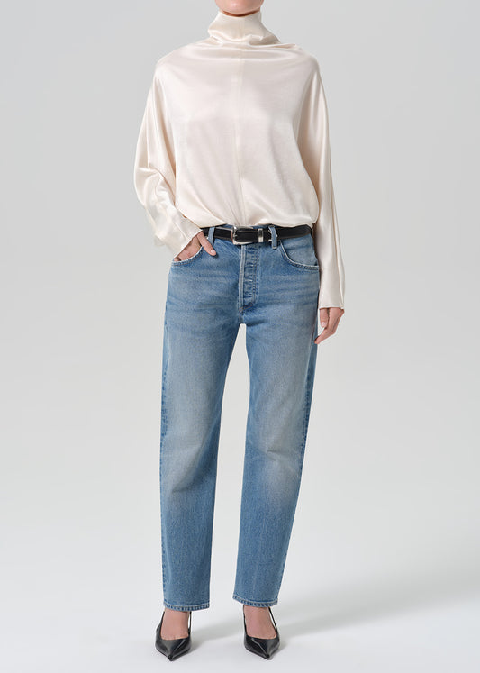 Person wearing blue jeans with cream color satin top