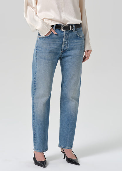 Person wearing blue jeans with cream color satin top