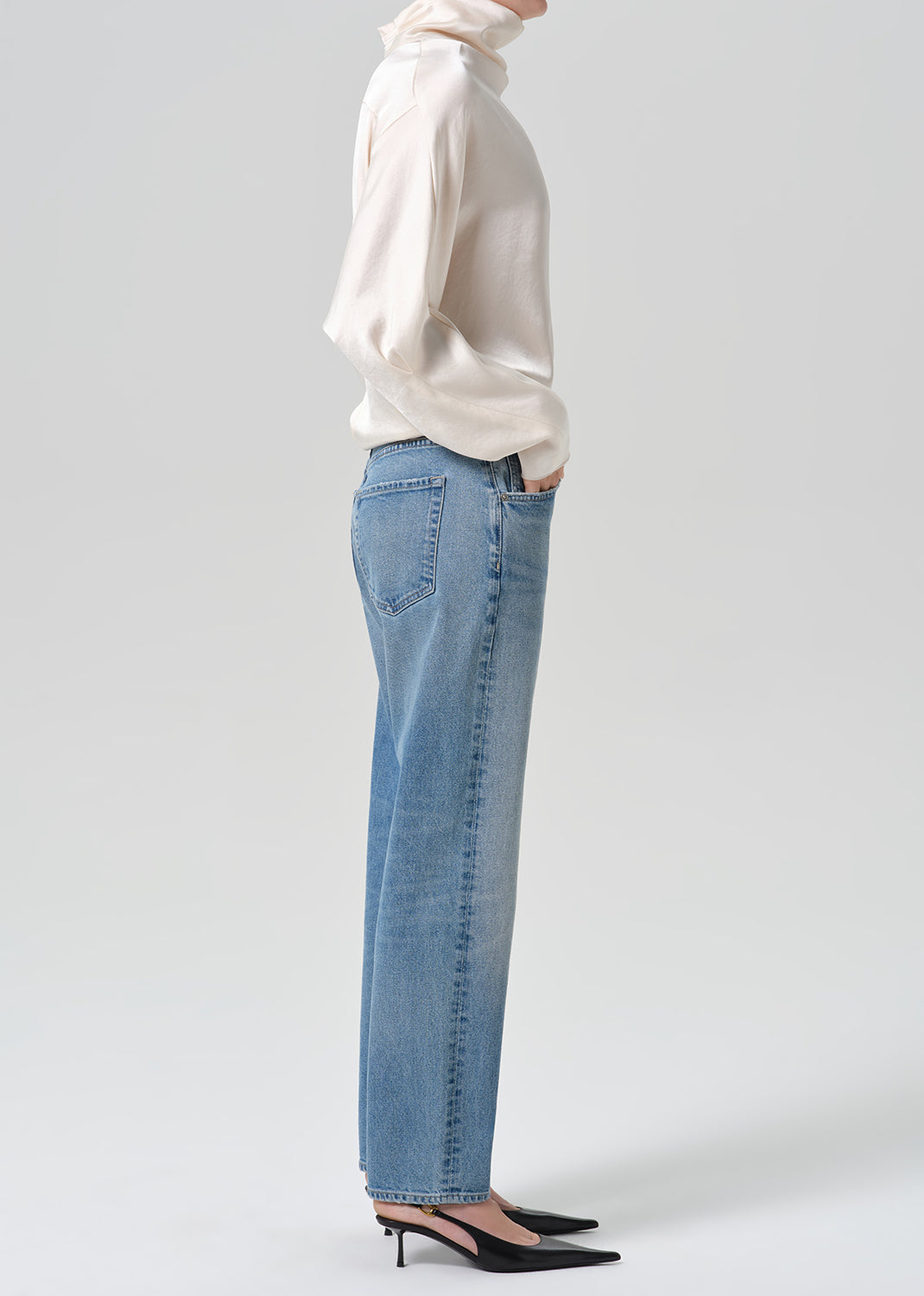 Person wearing blue jeans with cream color satin top