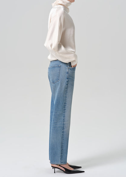 Person wearing blue jeans with cream color satin top