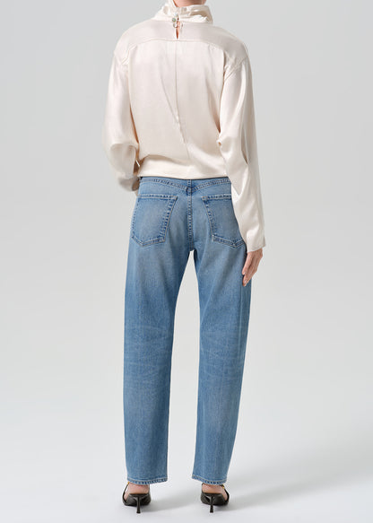 Person wearing blue jeans with cream color satin top