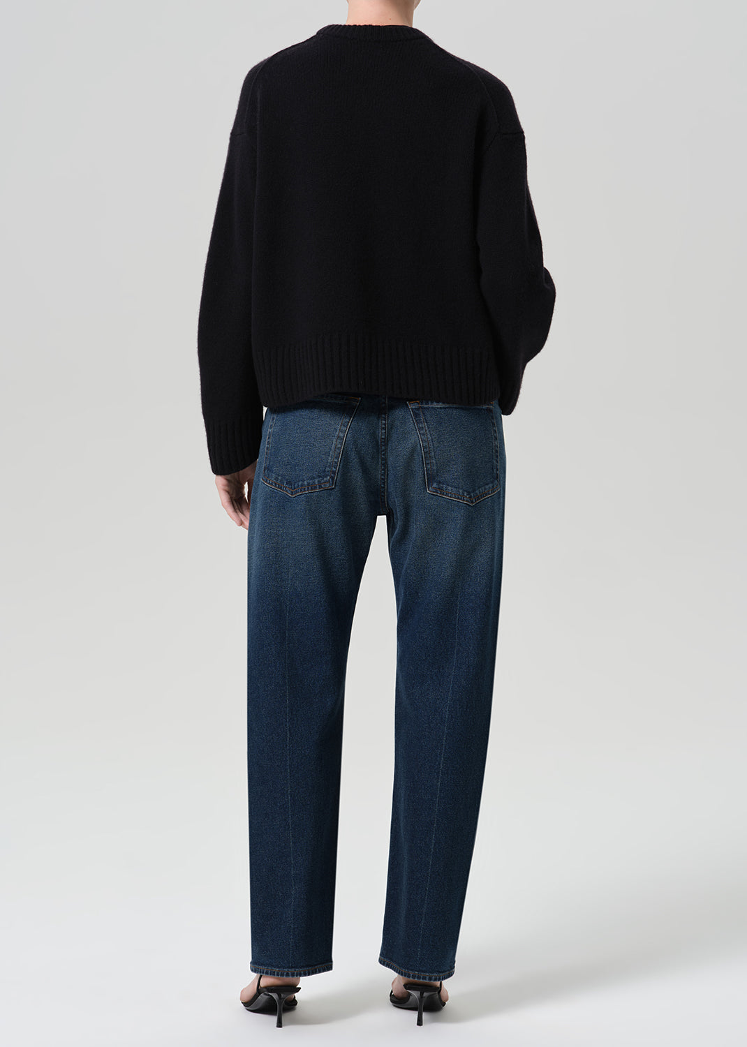Person wearing dark indigo jeans paired with sweater