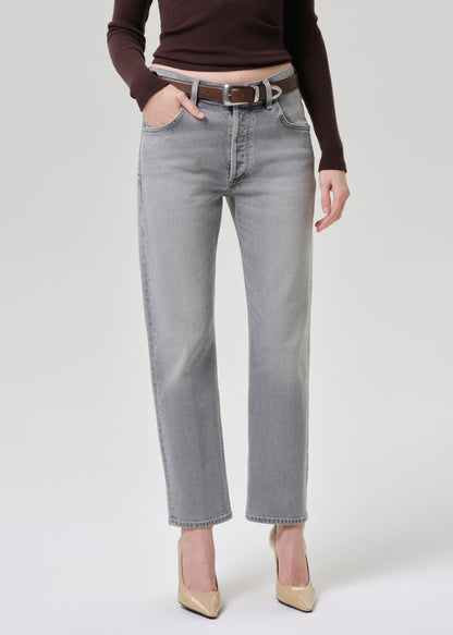 Person wearing light gray jeans with a brown belt on a grey background