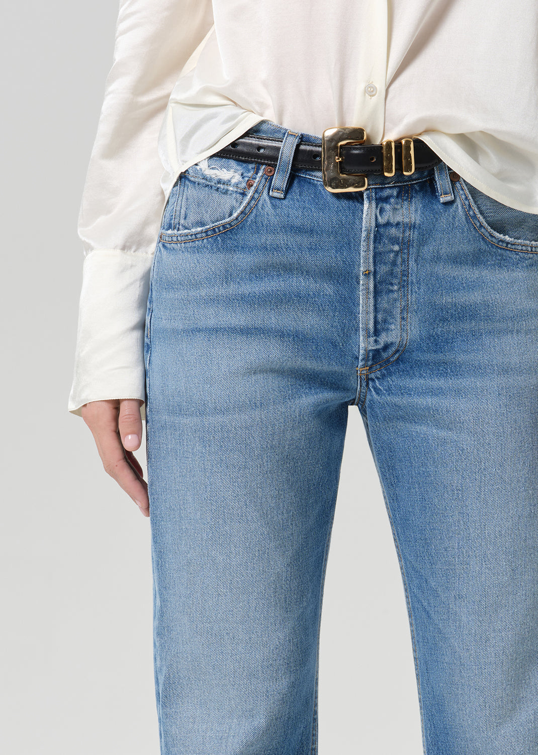 Person wearing medium indigo jeans paired with cream color shirt