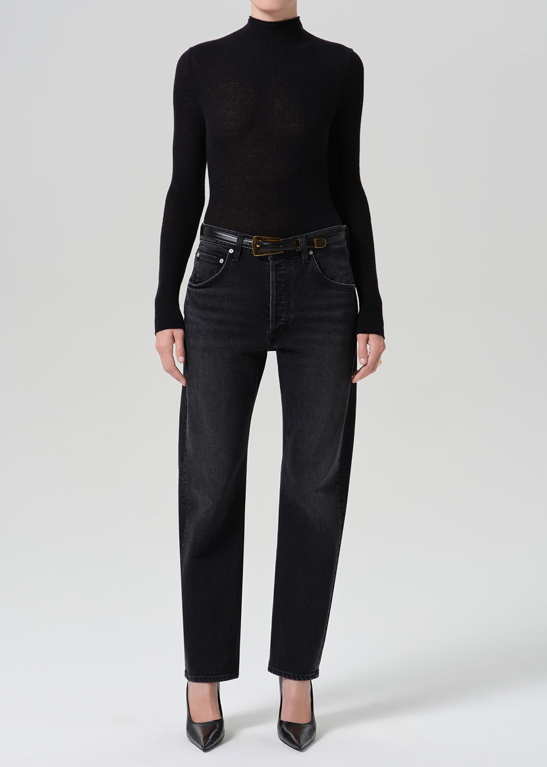Person wearing washed black jeans paired with black turtleneck