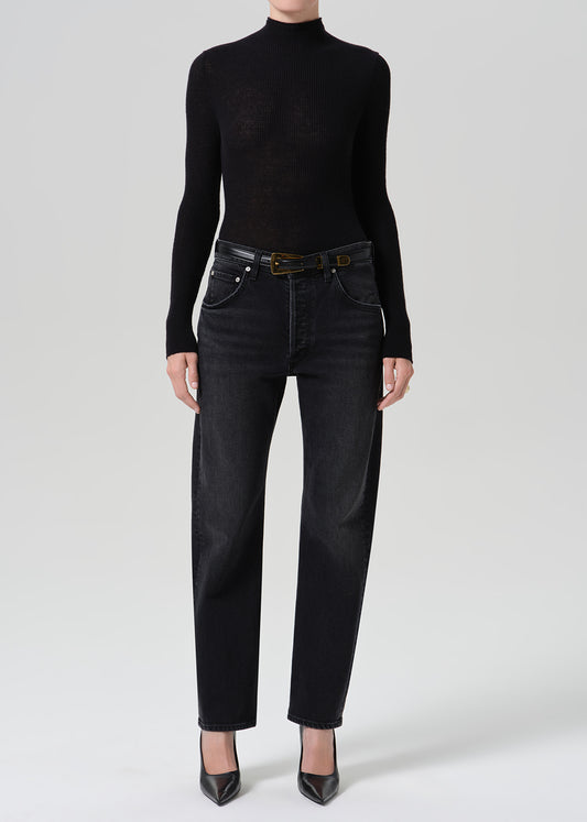 Person wearing washed black jeans paired with black turtleneck