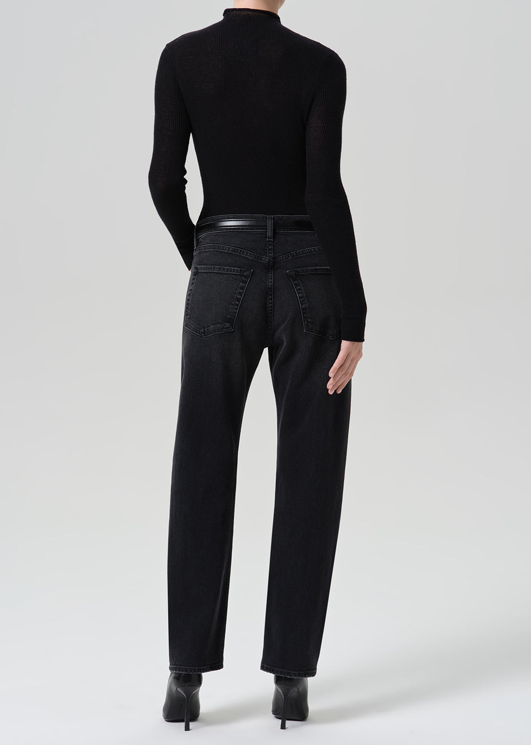 Person wearing washed black jeans paired with black turtleneck