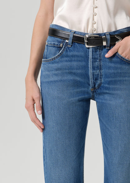 Person wearing medium wash straight leg jeans on a grey background