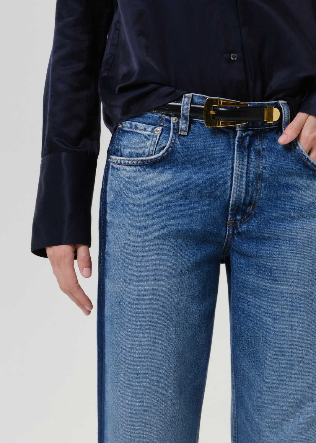 Close-up of medium blue wide leg jeans on a grey background.