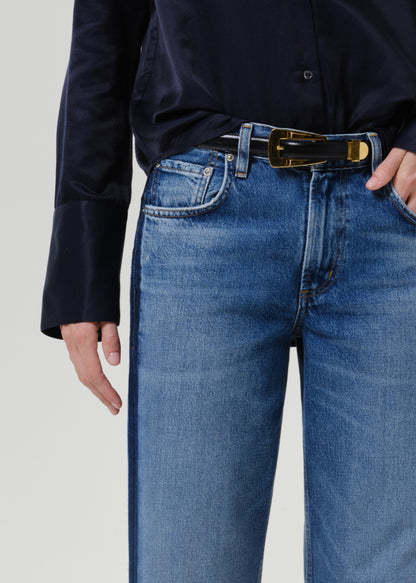 Close-up of medium blue wide leg jeans on a grey background.