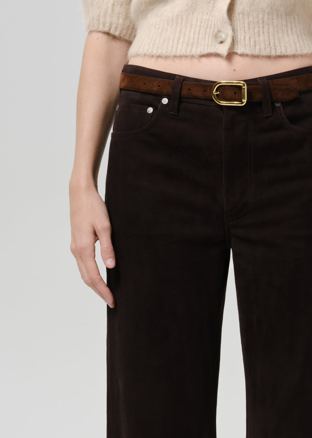 Close-up of dark brown straight leg trousers on a grey background