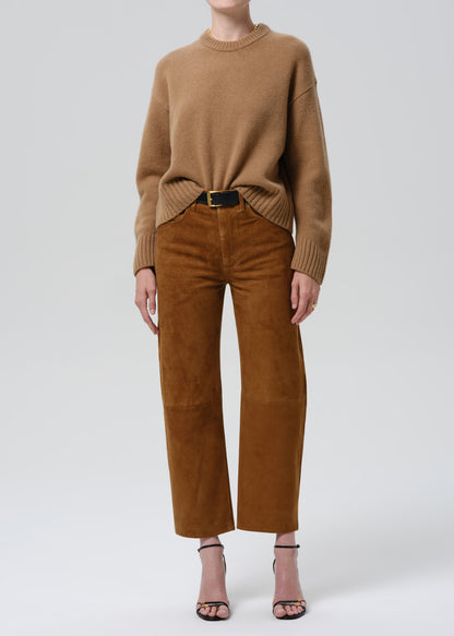 Person wearing a brown sweater and matching pants on a grey background.
