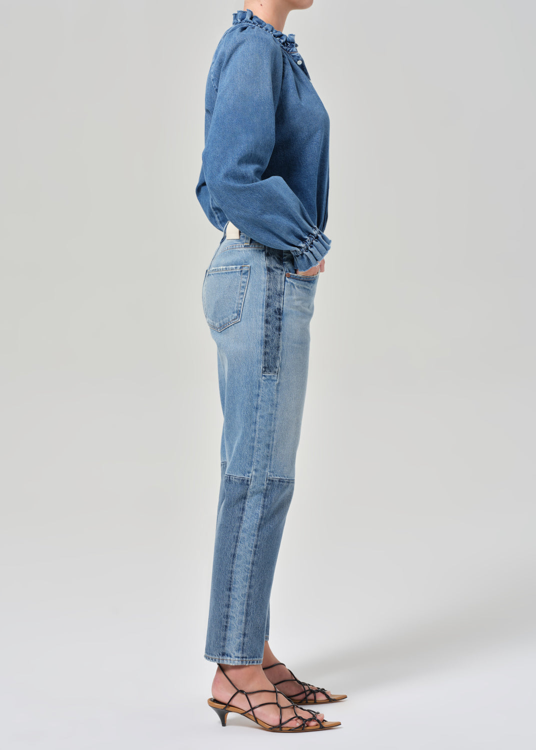 Person wearing a blue denim shirt and jeans on a plain background