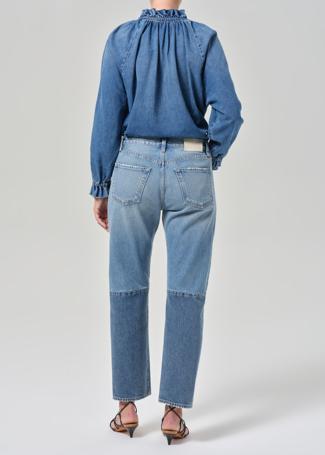 Person wearing a blue denim shirt and jeans on a white background