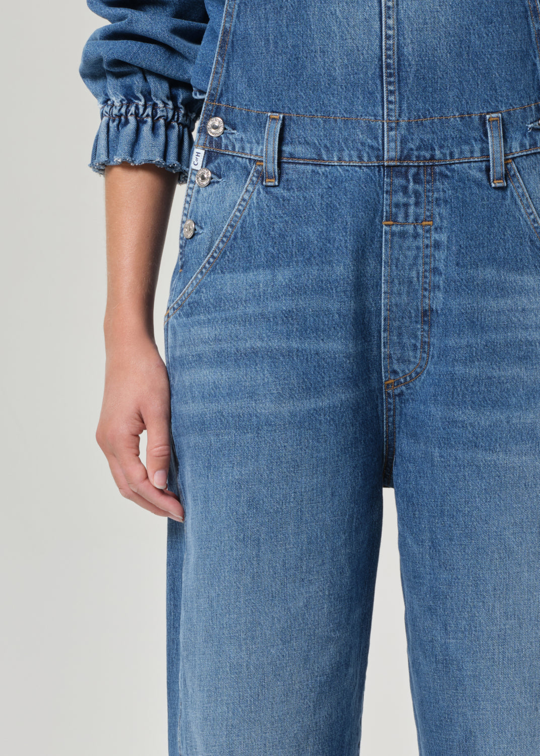 Close-up of blue jeans overall with a plain background