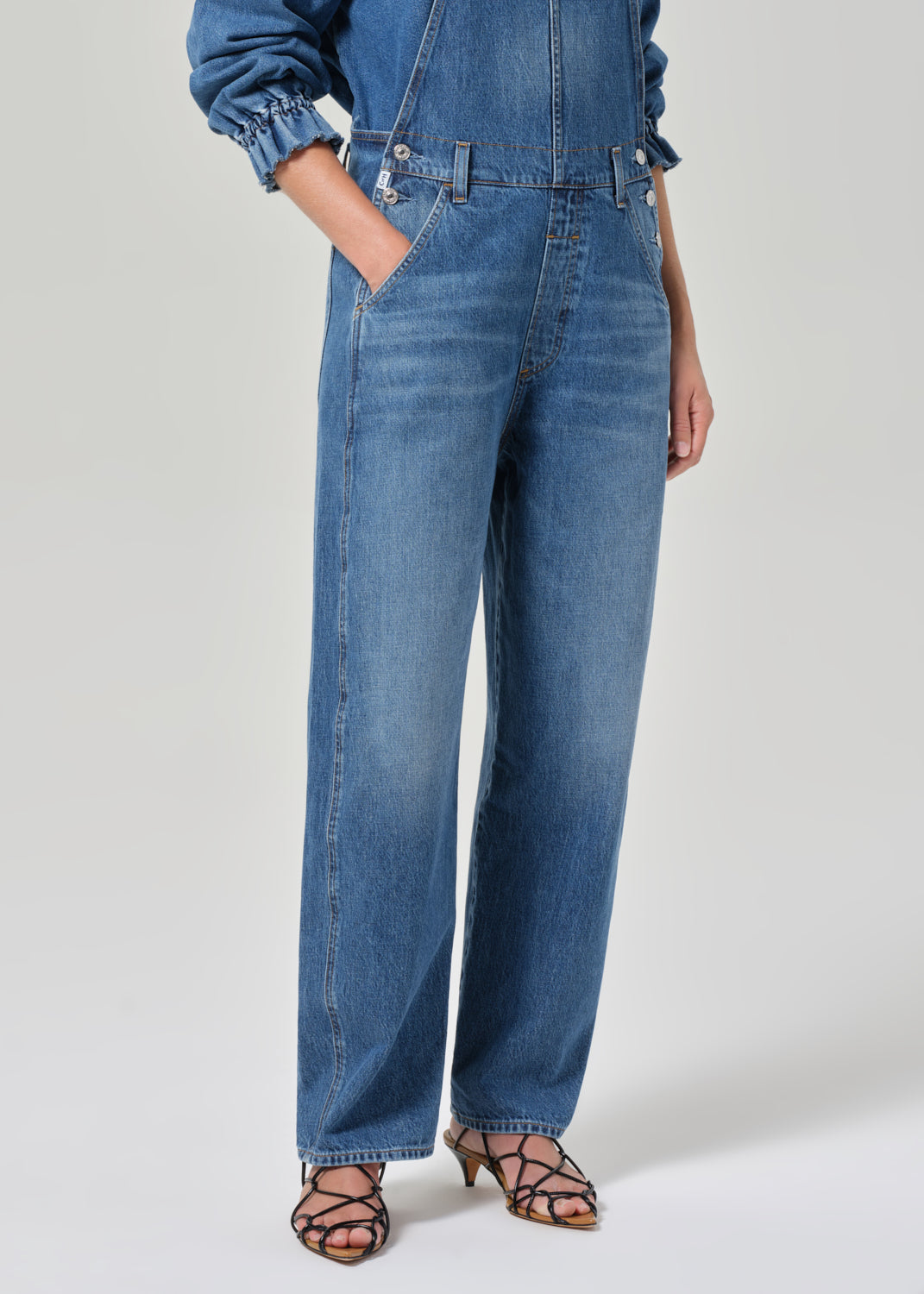 Person wearing a blue denim overall on a white background