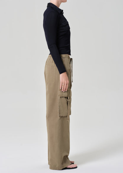 Person wearing a black shirt and beige cargo pants on a plain background