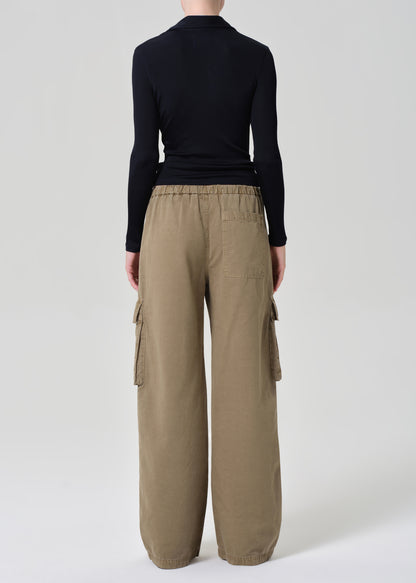 Person wearing a black shirt and beige cargo pants on a plain background
