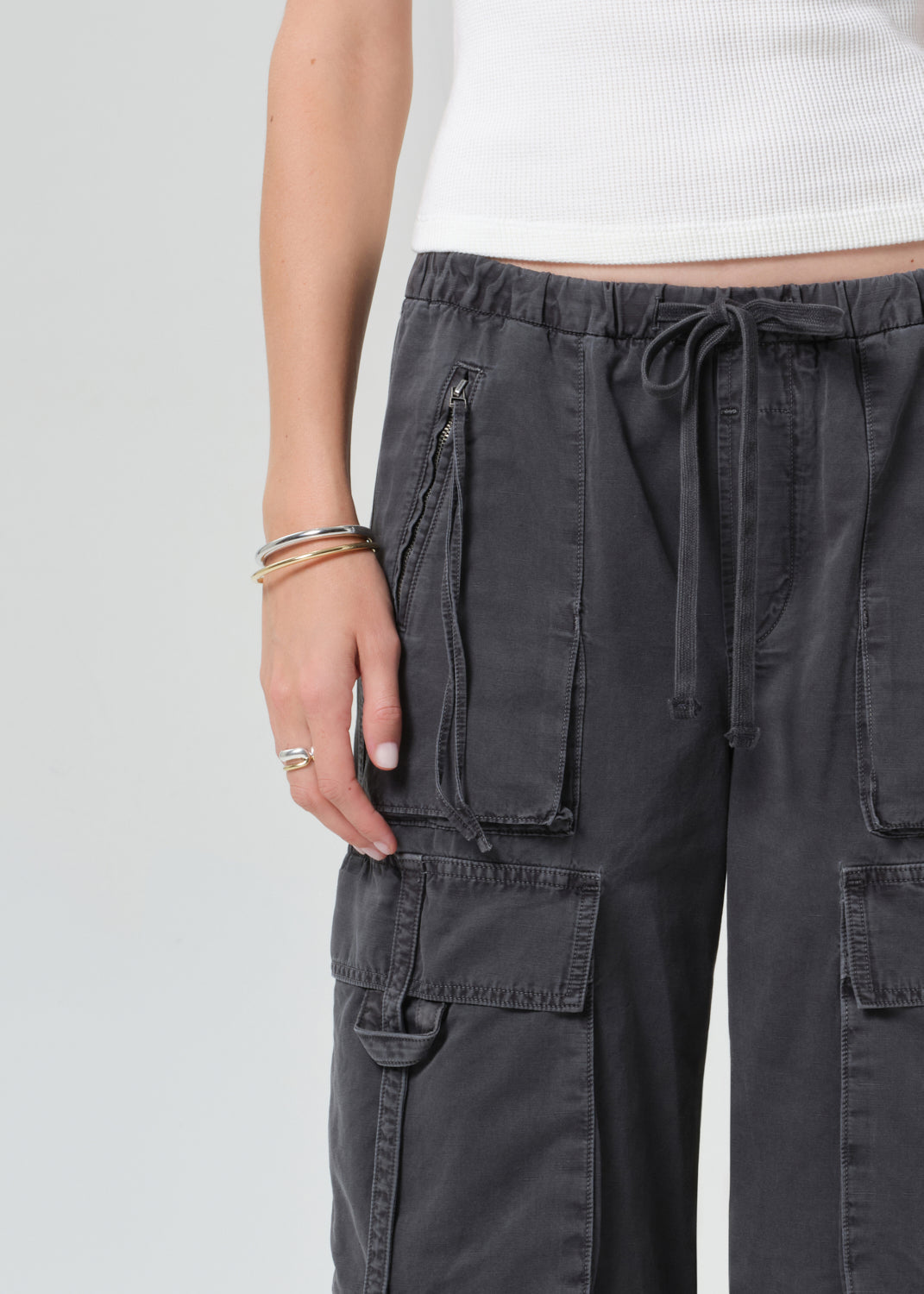 Person wearing a white tee with dark gray cargo pants on a plain background