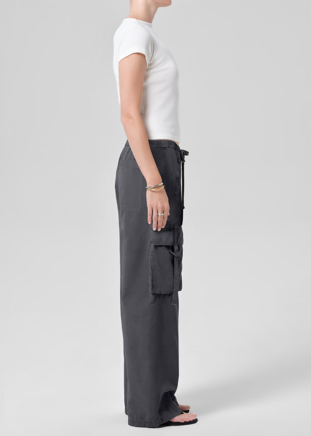 Person wearing a white tee with dark gray cargo pants on a plain background