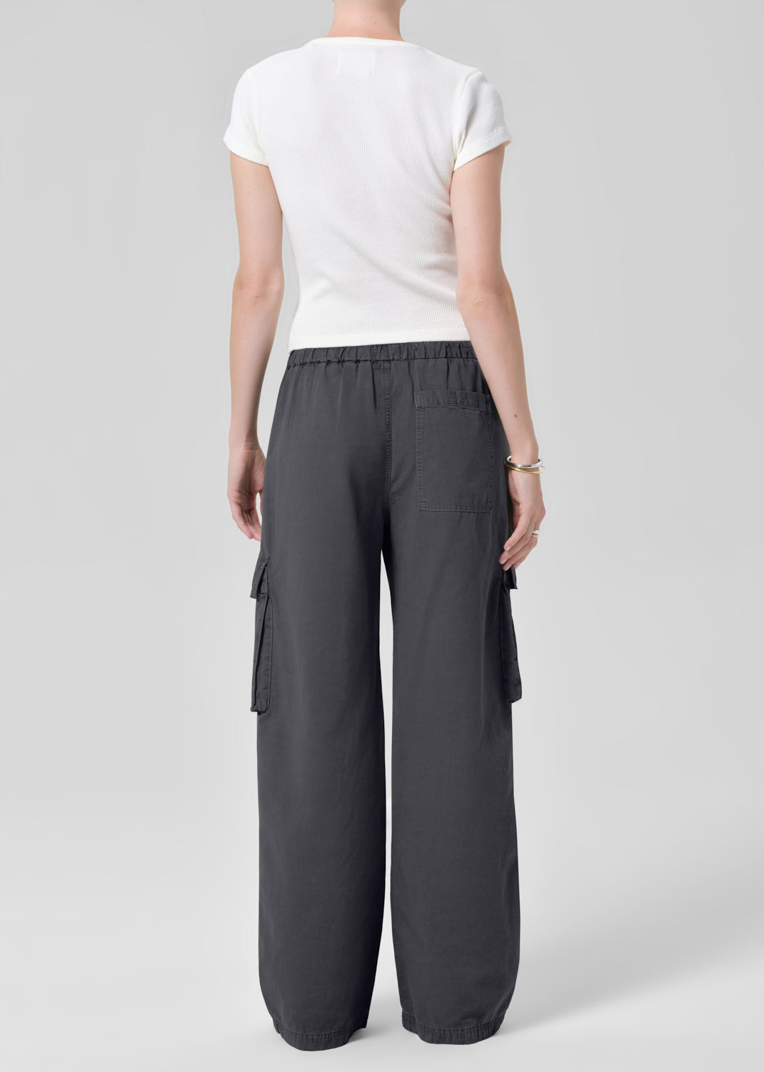 Person wearing a white tee with dark gray cargo pants on a plain background