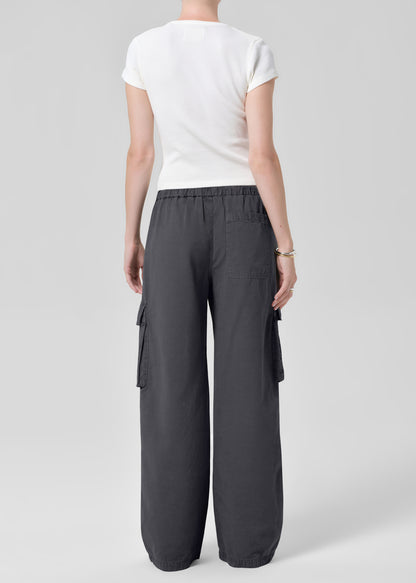 Person wearing a white tee with dark gray cargo pants on a plain background
