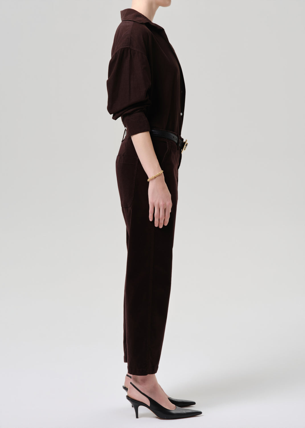 Person wearing a brown outfit with a jacket and pants on a grey background