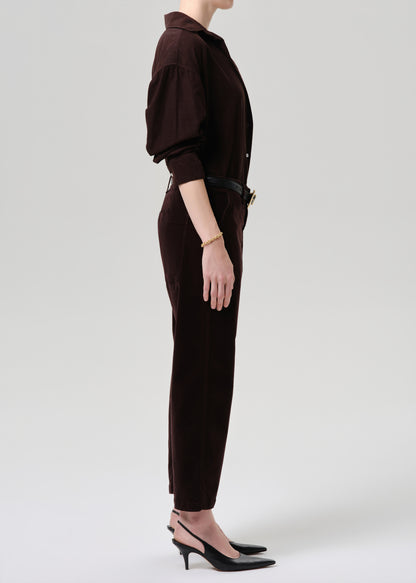 Person wearing a brown outfit with a jacket and pants on a grey background