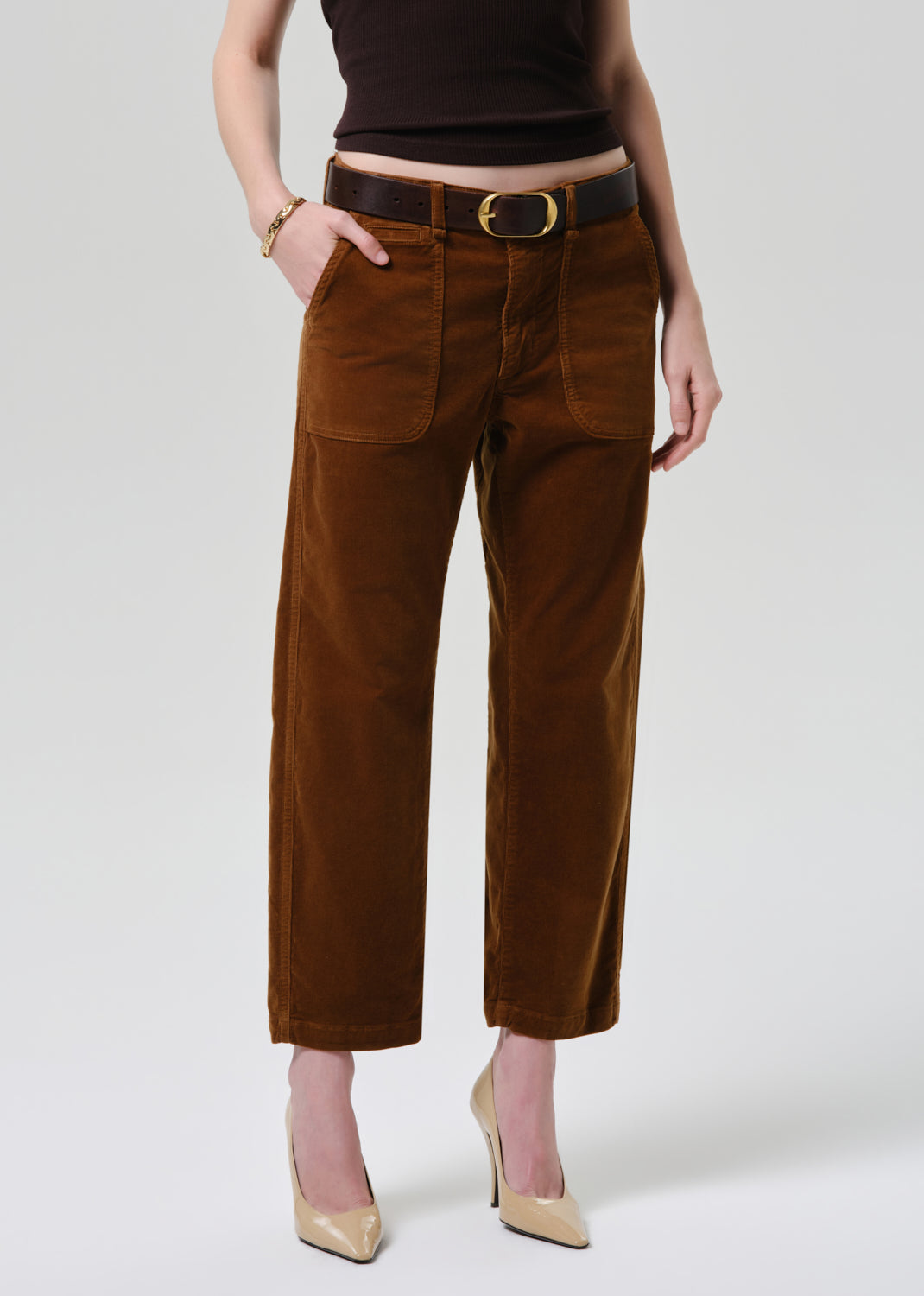 Brown corduroy pants worn by a person on a grey background