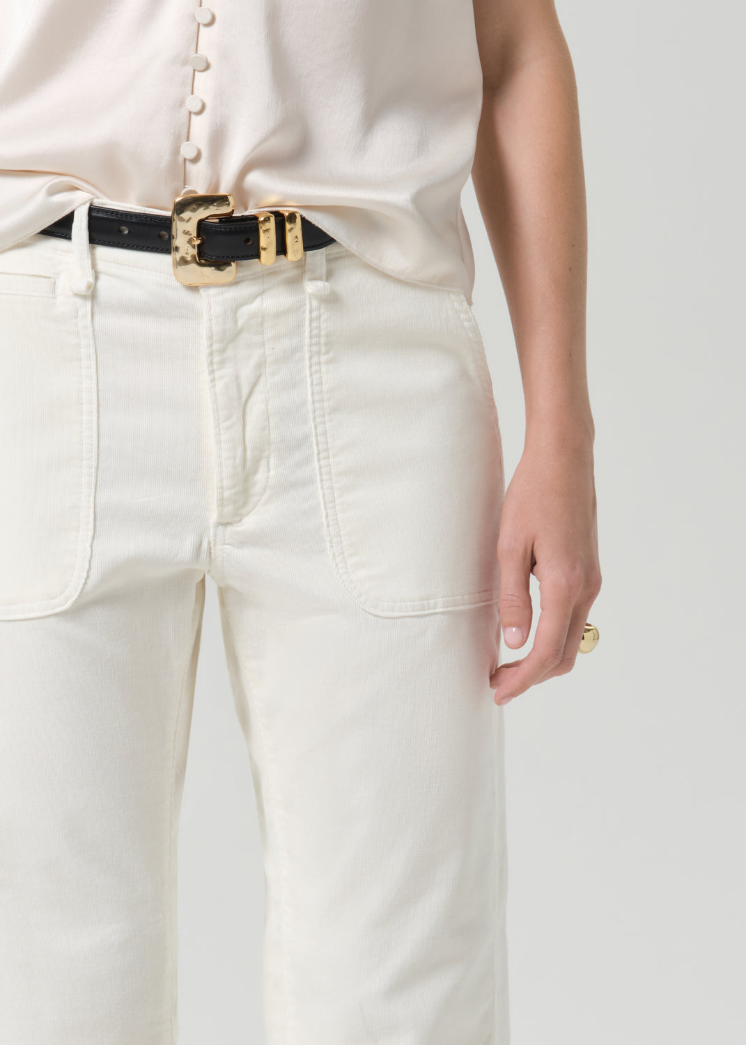 Close up of white pant and black belt on a grey background