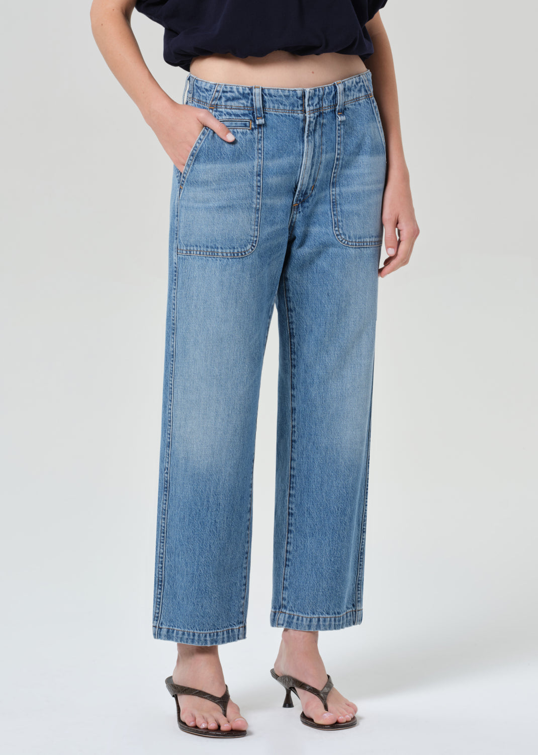 Person wearing blue jeans on a grey background