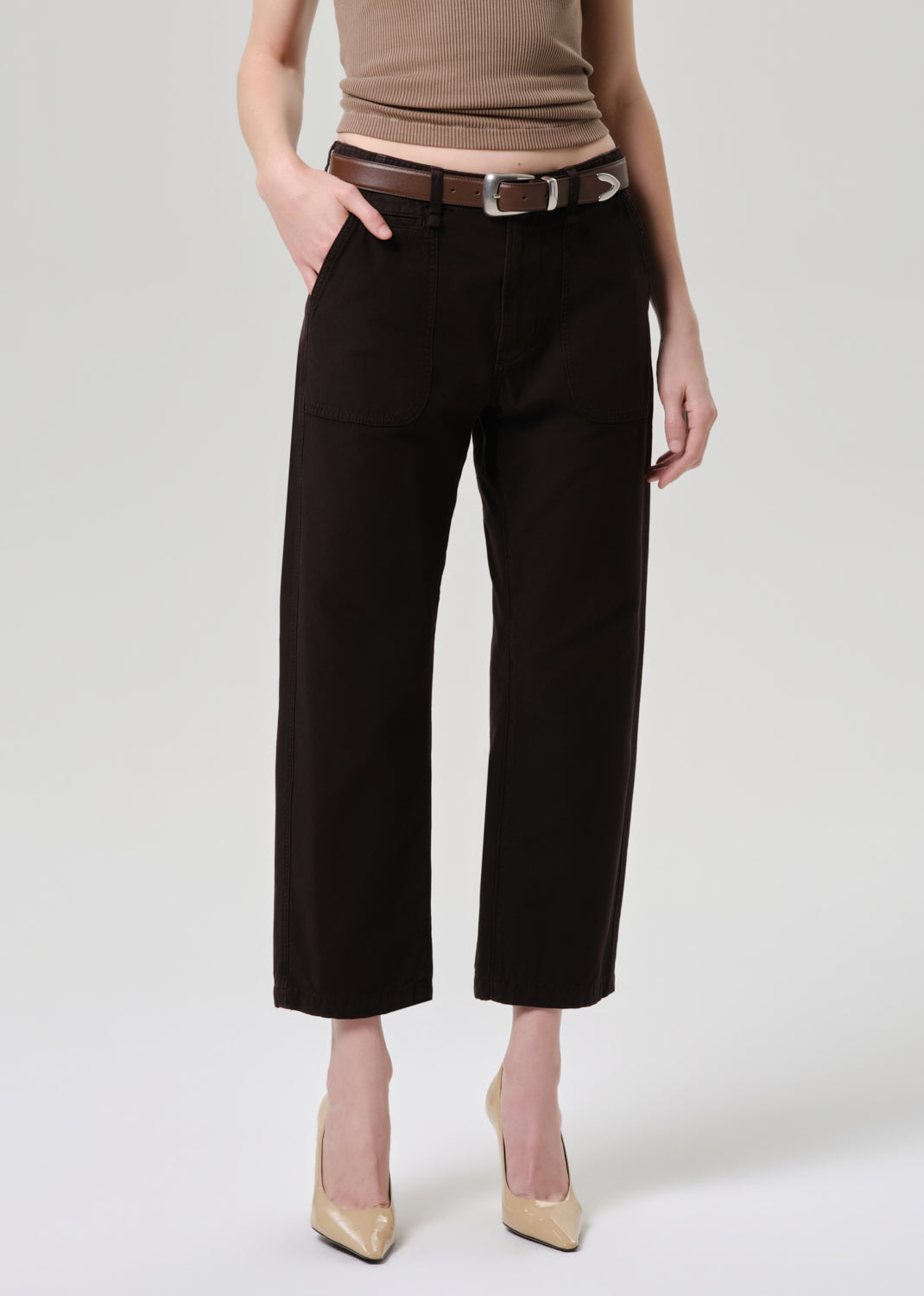 Person wearing black pants with a brown belt on a grey background