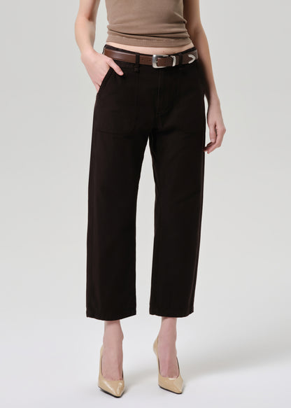 Person wearing black pants with a brown belt on a grey background